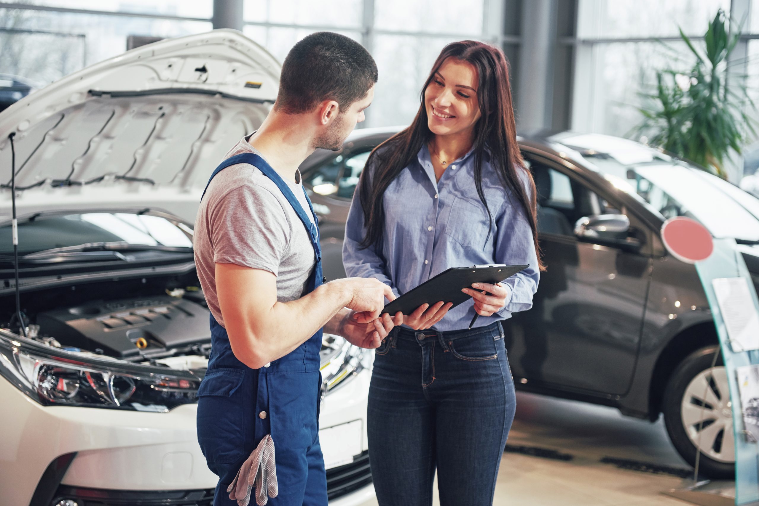 A man mechanic and woman customer discussing repairs done to her vehicle.